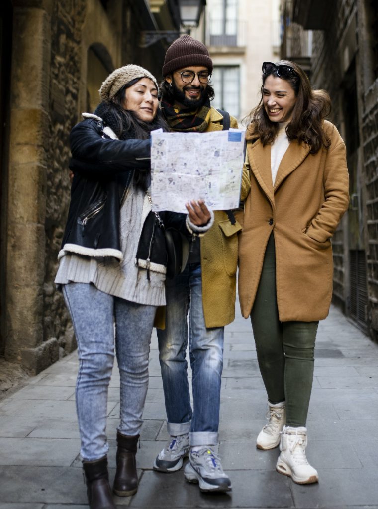 Three multiracial tourists friends looking map on city street outdoors - Fun, friends, travel and